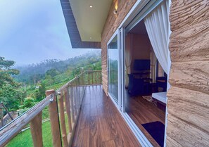 A balcony with a wooden floor and glass railing, overlooking a lush green landscape. - The Treetop Escape by VOYE HOMES (Peermade)