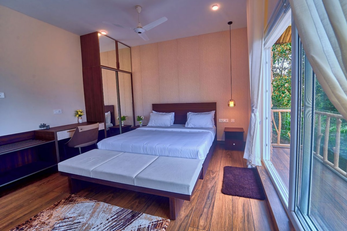 Quarto moderno com uma cama grande, piso de madeira, ventilador de teto e vista para o exterior.