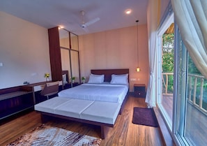 Quarto moderno com uma cama grande, piso de madeira, ventilador de teto e vista para o exterior.