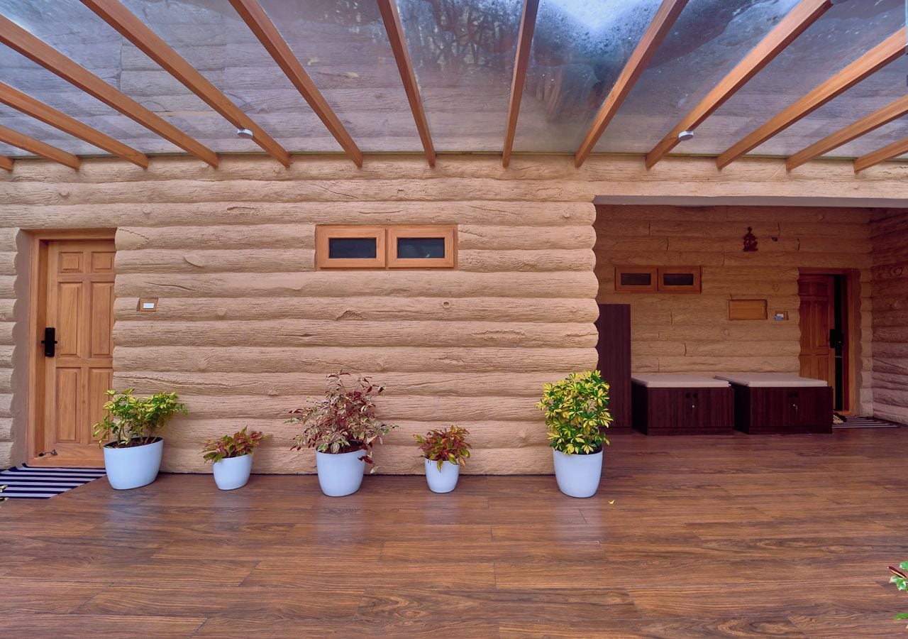 Una cabaña de troncos con piso de madera, techo de cristal y plantas en macetas.