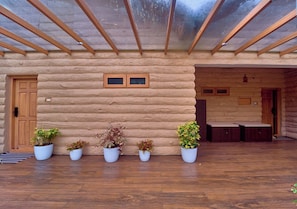 A log cabin with a wooden floor, a glass ceiling, and potted plants.