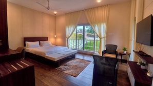 A hotel room with a bed, a desk, a chair, a TV, and a balcony with curtains. - The Treetop Escape by VOYE HOMES (Peermade)