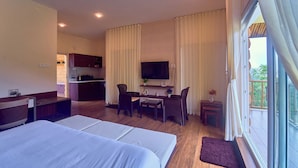 A hotel room with a large bed, a desk, a chair, a television, and a view of the outdoors.