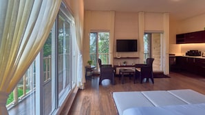 A hotel room with a large bed, a desk with a chair, a television, and a view of the outdoors. - The Treetop Escape by VOYE HOMES (Peermade)