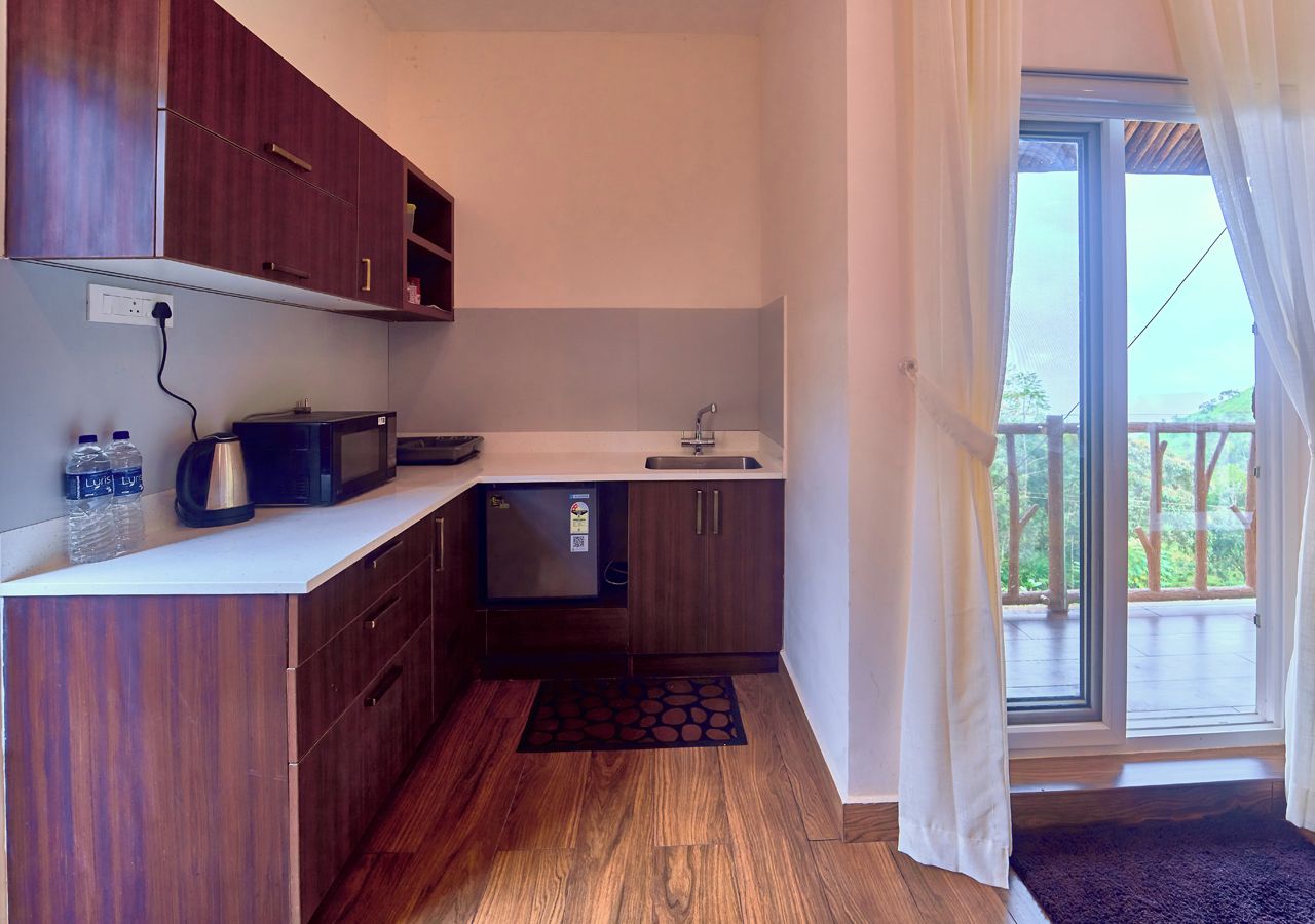 Una cucina compatta con mobili in legno, un forno a microonde e un lavello.