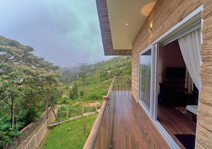 A modern building with a balcony overlooking a lush green landscape. - The Treetop Escape by VOYE HOMES (Peermade)