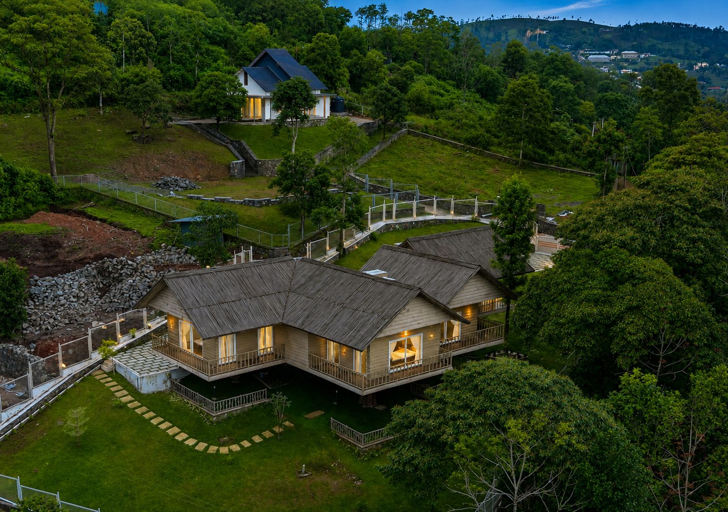 Una grande casa a due piani in legno, con un balcone, immersa nel verde e circondata da un terreno recintato.