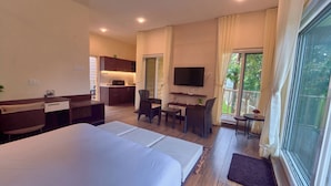 A hotel room with a large bed, a desk, a chair, a television, and a view of the outdoors. - The Treetop Escape by VOYE HOMES (Peermade)