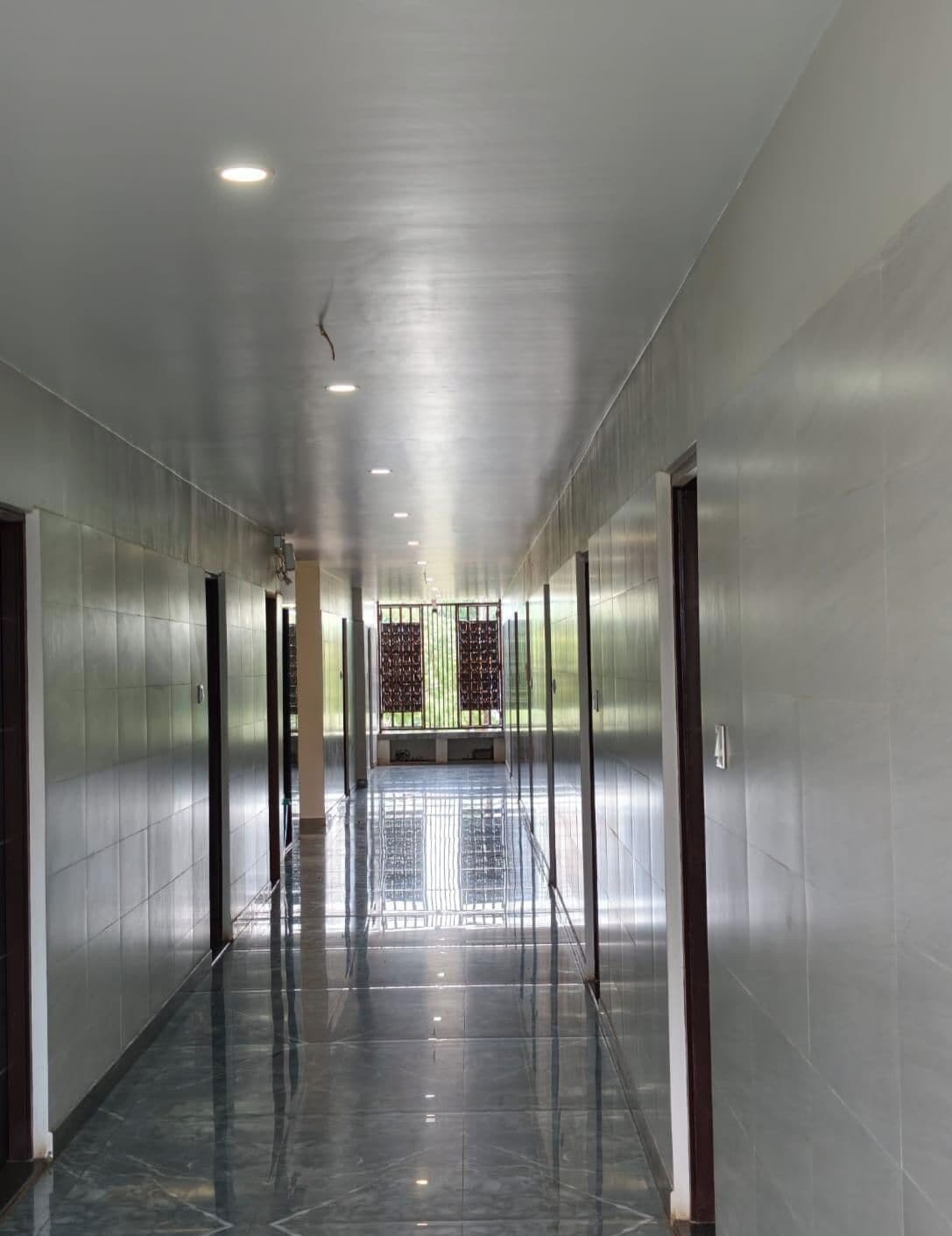 A long, narrow hallway with a shiny floor, doors on both sides, and a gate at the end.