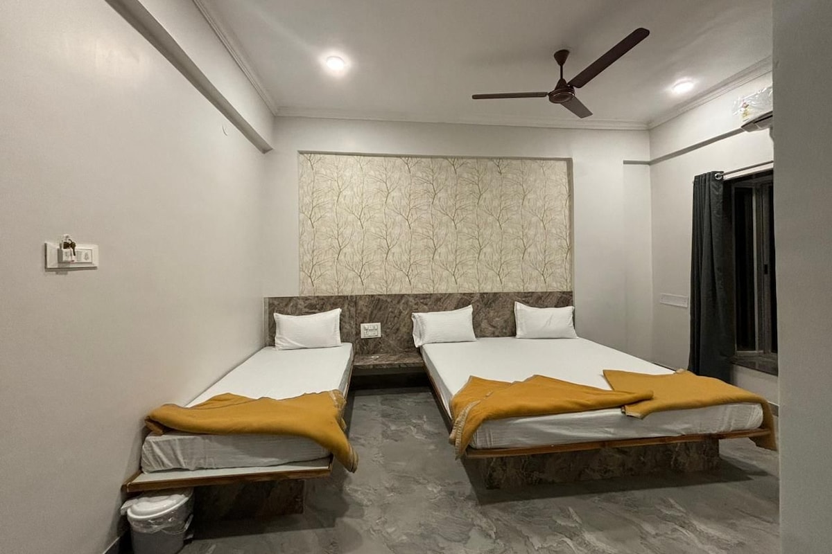 A hotel room with two beds, a ceiling fan, a marble-patterned wall, and a window with curtains.