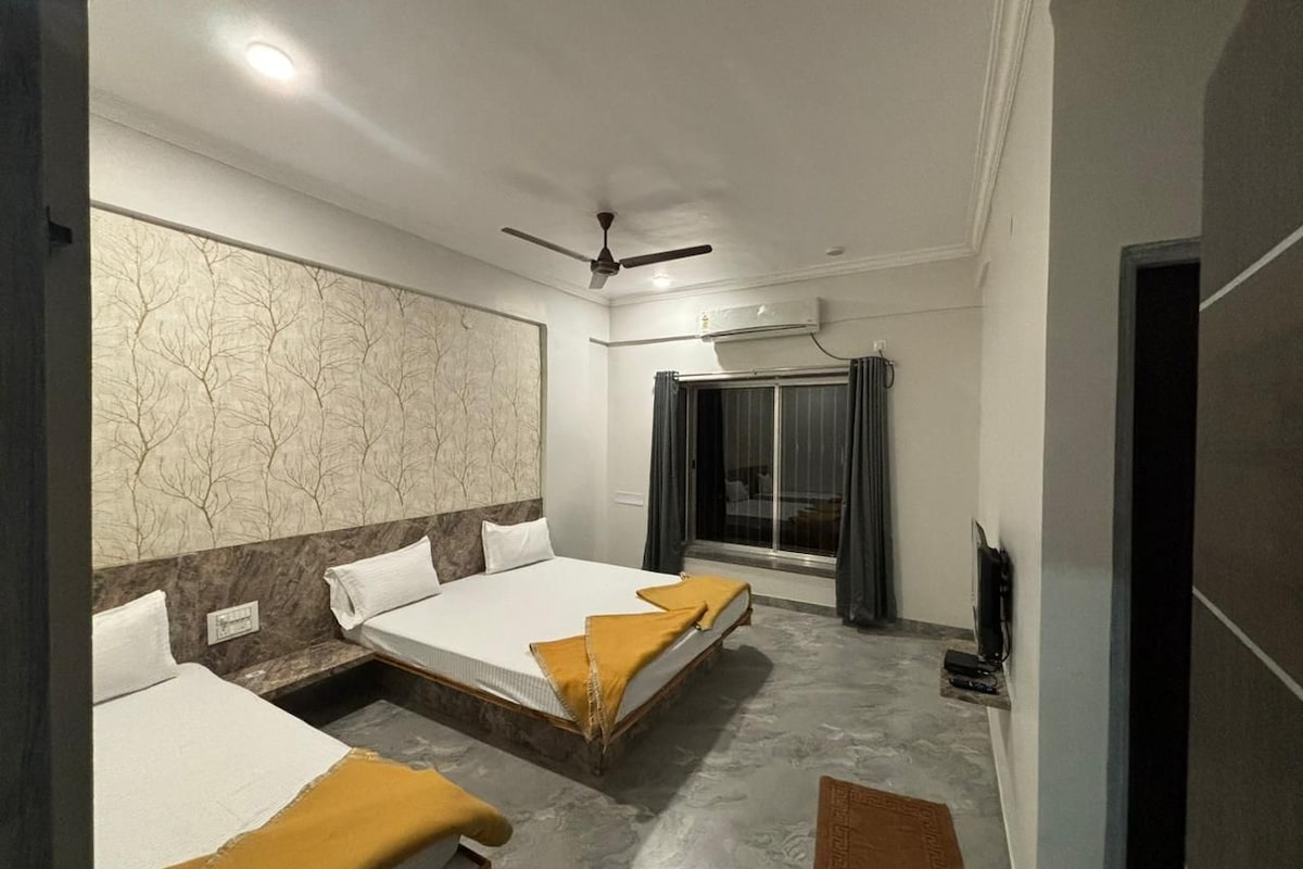 A hotel room with two beds, a ceiling fan, an air conditioning unit, a television, and a window with curtains.