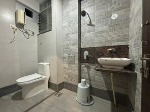 A modern bathroom with a toilet, shower, and sink. - Hotel Grand Vrundavan (Akalkot)