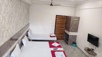 A hotel room with two single beds, a wardrobe, a television, and a ceiling fan.