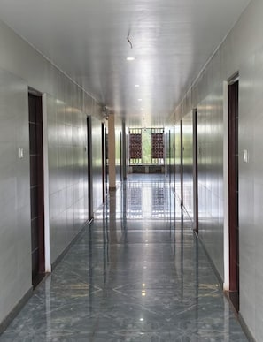 A corridor with a shiny marble floor, metallic walls, and doors leading to elevators.