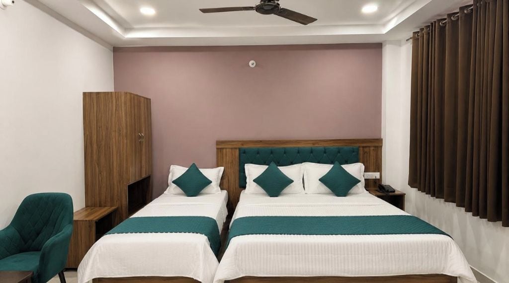 Una habitación de hotel con dos camas, un armario, un escritorio y una silla.