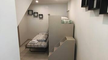 Ein kleiner Raum mit einem Bett, einer Treppe und einer Wandregal-Kombination.