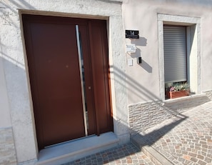 A building entrance with a brown door, a mailbox, and a sign indicating a vacant property.