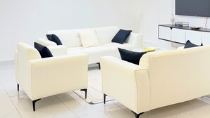 Un soggiorno moderno con un divano componibile, una televisione a schermo piatto e una lampada a sospensione decorativa.