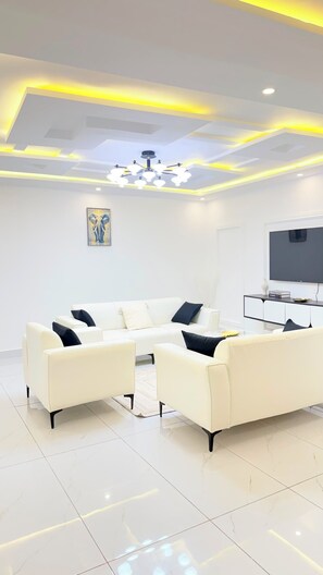 A modern living room with a sectional sofa, a flat-screen TV, and a decorative ceiling light. - ✨ Elegant 2-bedroom apartment with a terrace in Riviera Faya (Abidjan)