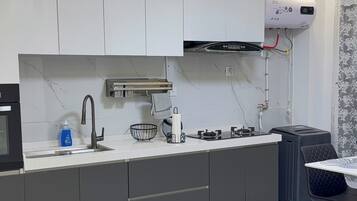 A modern kitchen with a white countertop, grey cabinets, a stainless steel faucet, and a built-in oven.