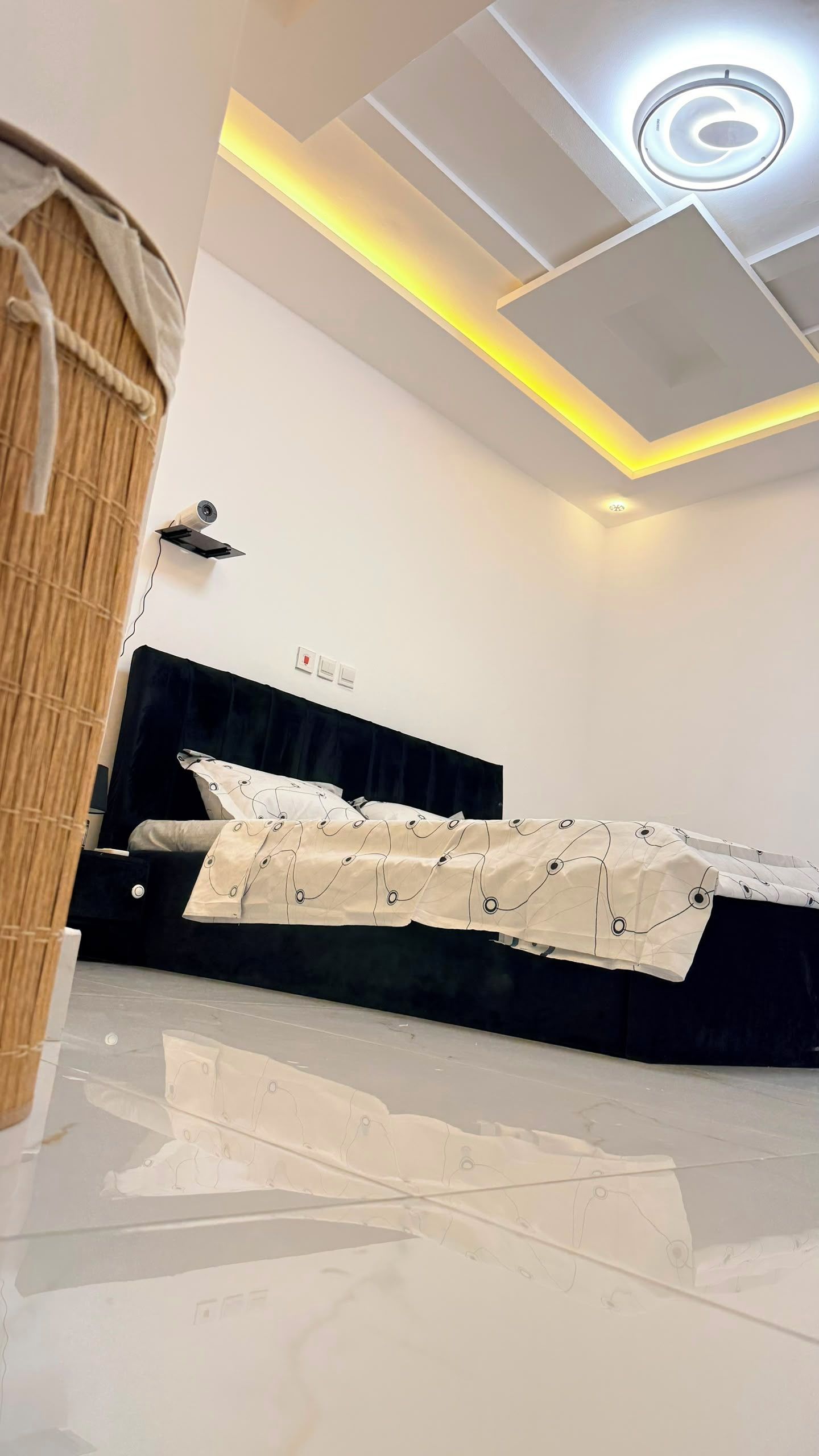 Une chambre à coucher avec un lit, un luminaire au plafond et un projecteur fixé au mur.