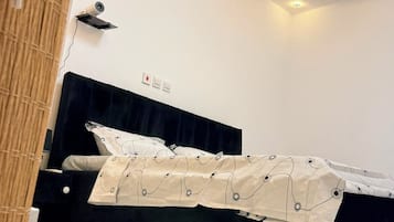 A bedroom with a bed, a ceiling light, and a wall-mounted projector.
