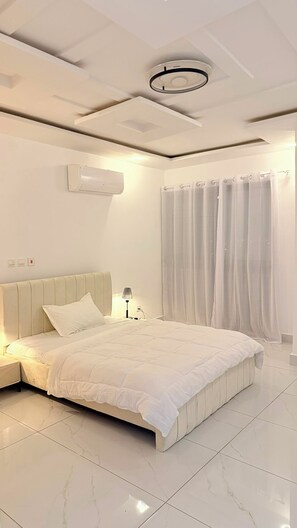 A modern bedroom with a bed, nightstand, lamp, air conditioning unit, and a ceiling light fixture. - ✨ Elegant 2-bedroom apartment with a terrace in Riviera Faya (Abidjan)