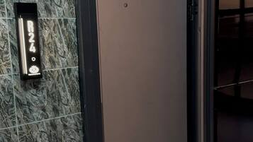 An elevator with a marble wall and a welcome mat at the entrance.