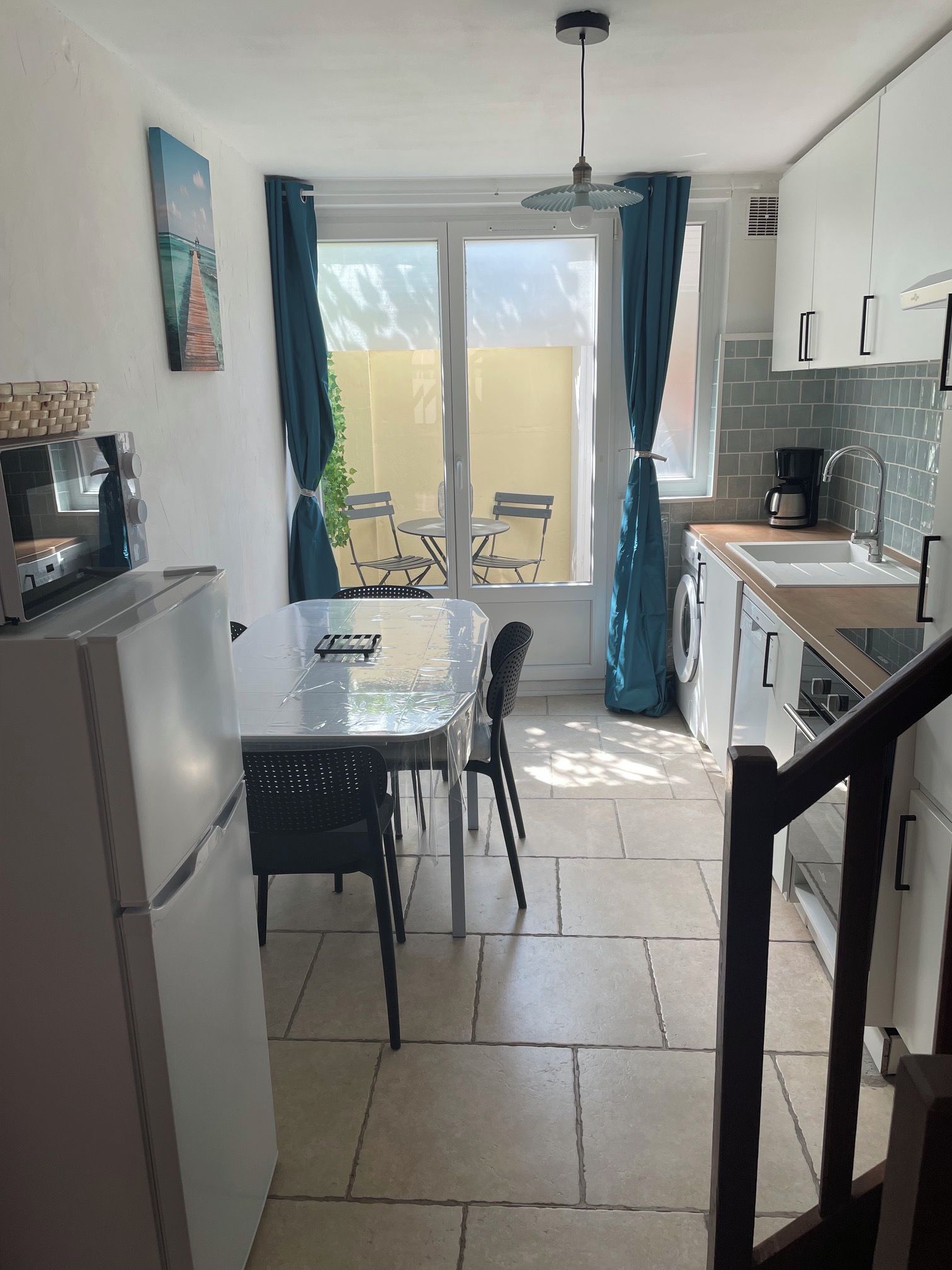 A compact kitchen with a dining area, a washing machine, and a coffee maker.