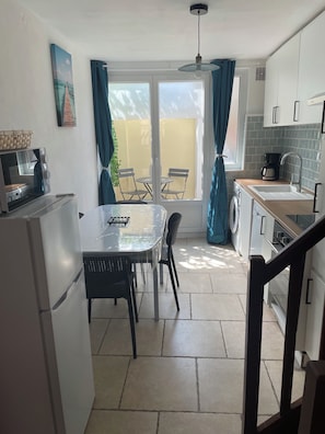 A compact kitchen with a dining area, a washing machine, and a coffee maker. - Fisherman's House   (Ault)