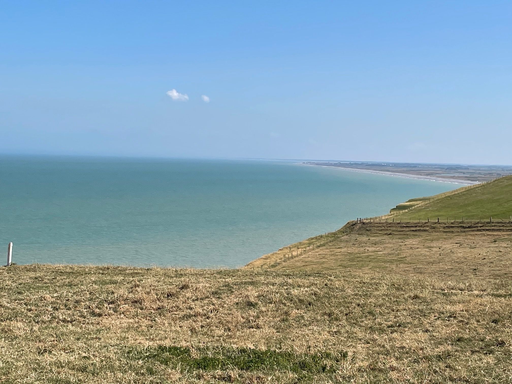 Eine Küstenlandschaft mit einer grasbewachsenen Vordergrund und Blick auf das Meer.