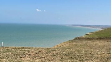 Eine Küstenlandschaft mit einer grasbewachsenen Vordergrund und Blick auf das Meer.
