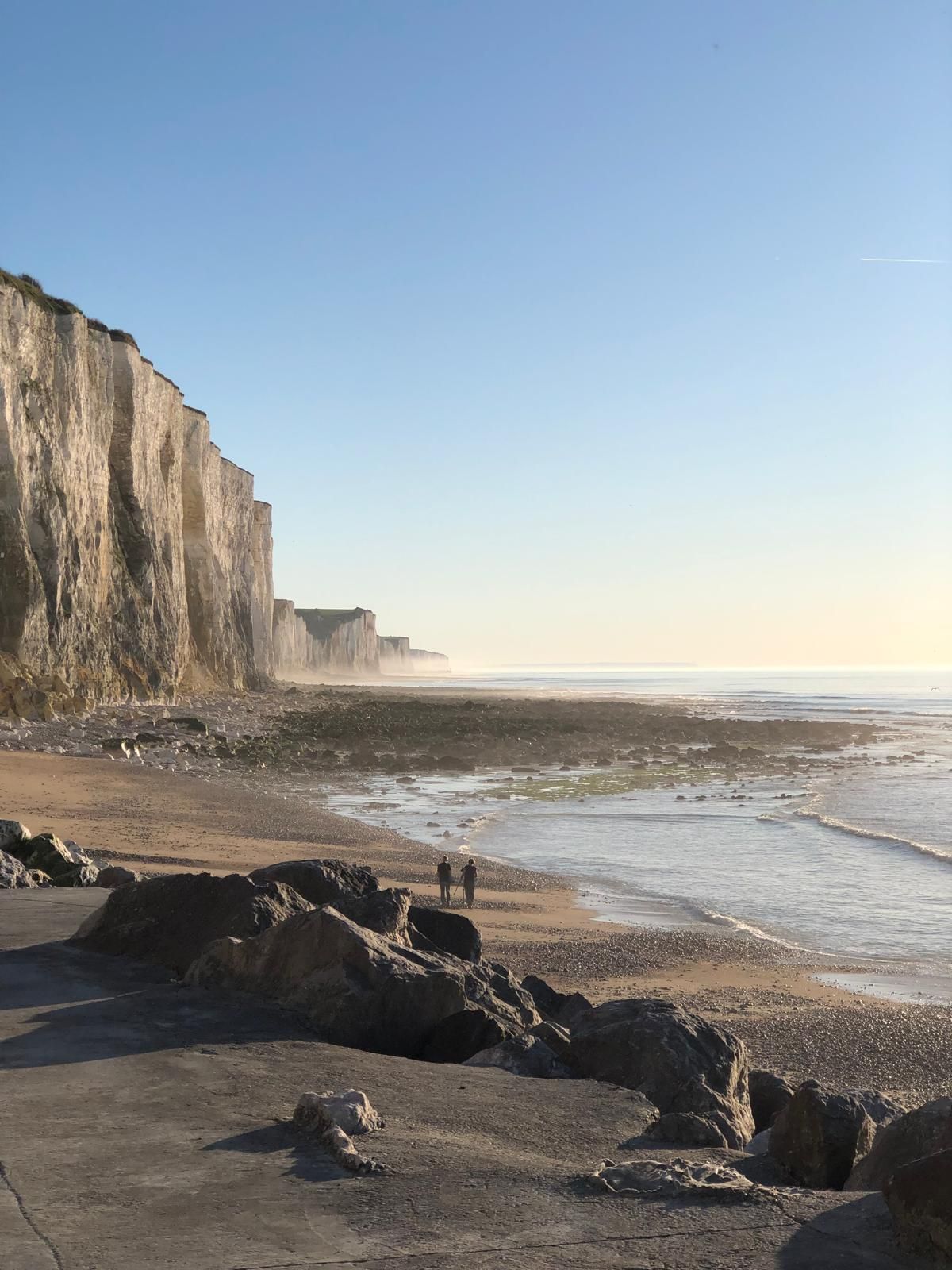 Un paysage côtier avec une plage rocheuse, des falaises et l’océan.