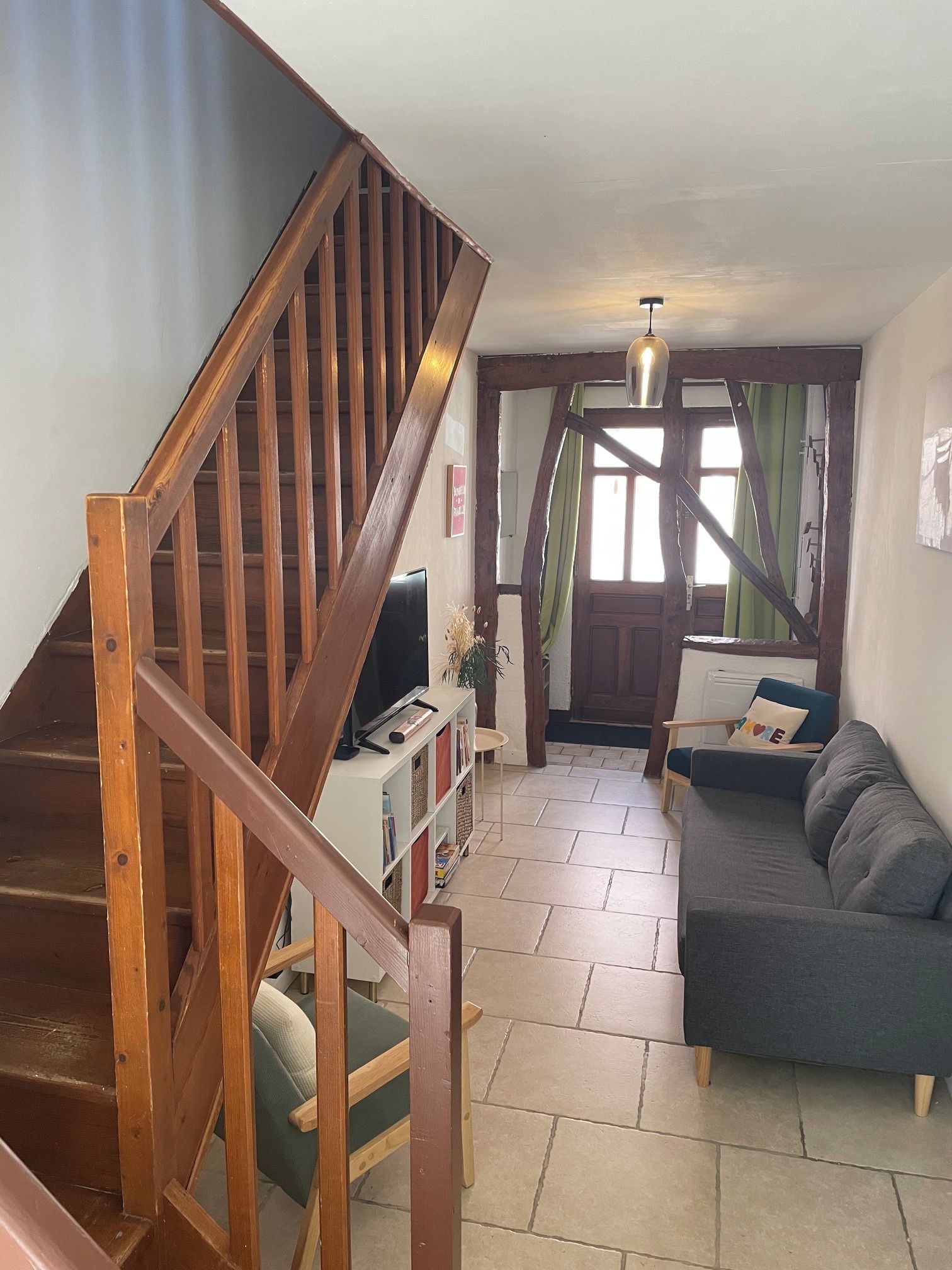 Un escalier menant à un salon équipé d’un canapé et d’un téléviseur.