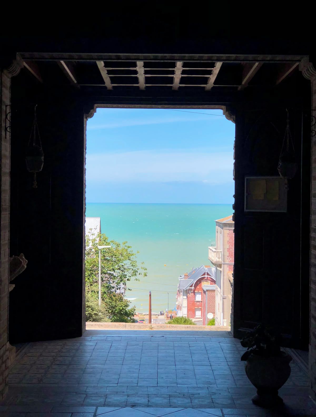 An open doorway leading to a view of the sea with buildings in the background.