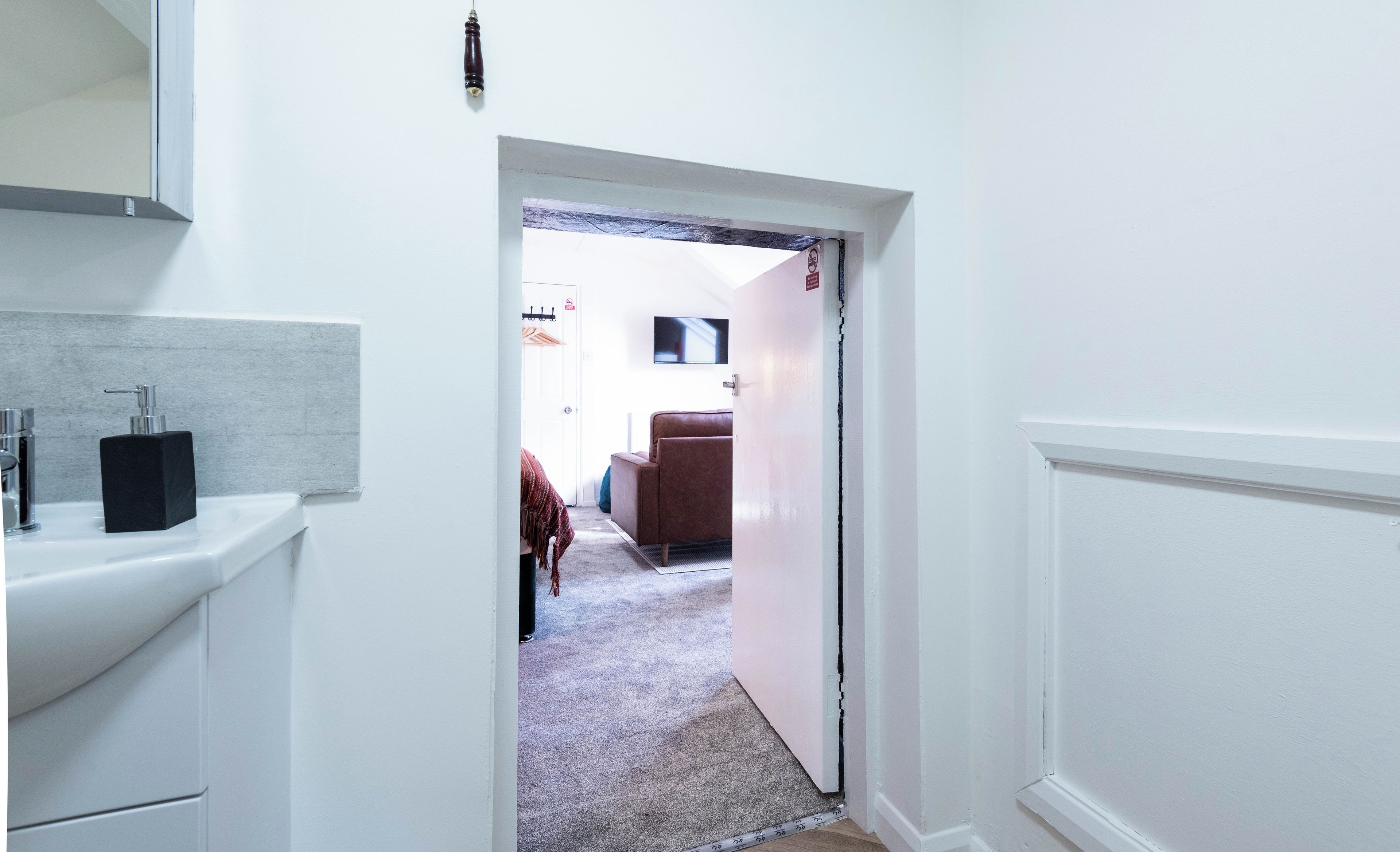 A hallway leading to a room with a bed, a television, and a door with a 'Do Not Disturb' sign.
