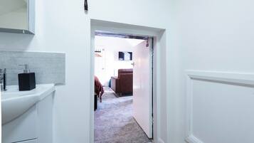 A hallway leading to a room with a bed, a television, and a door with a 'Do Not Disturb' sign.