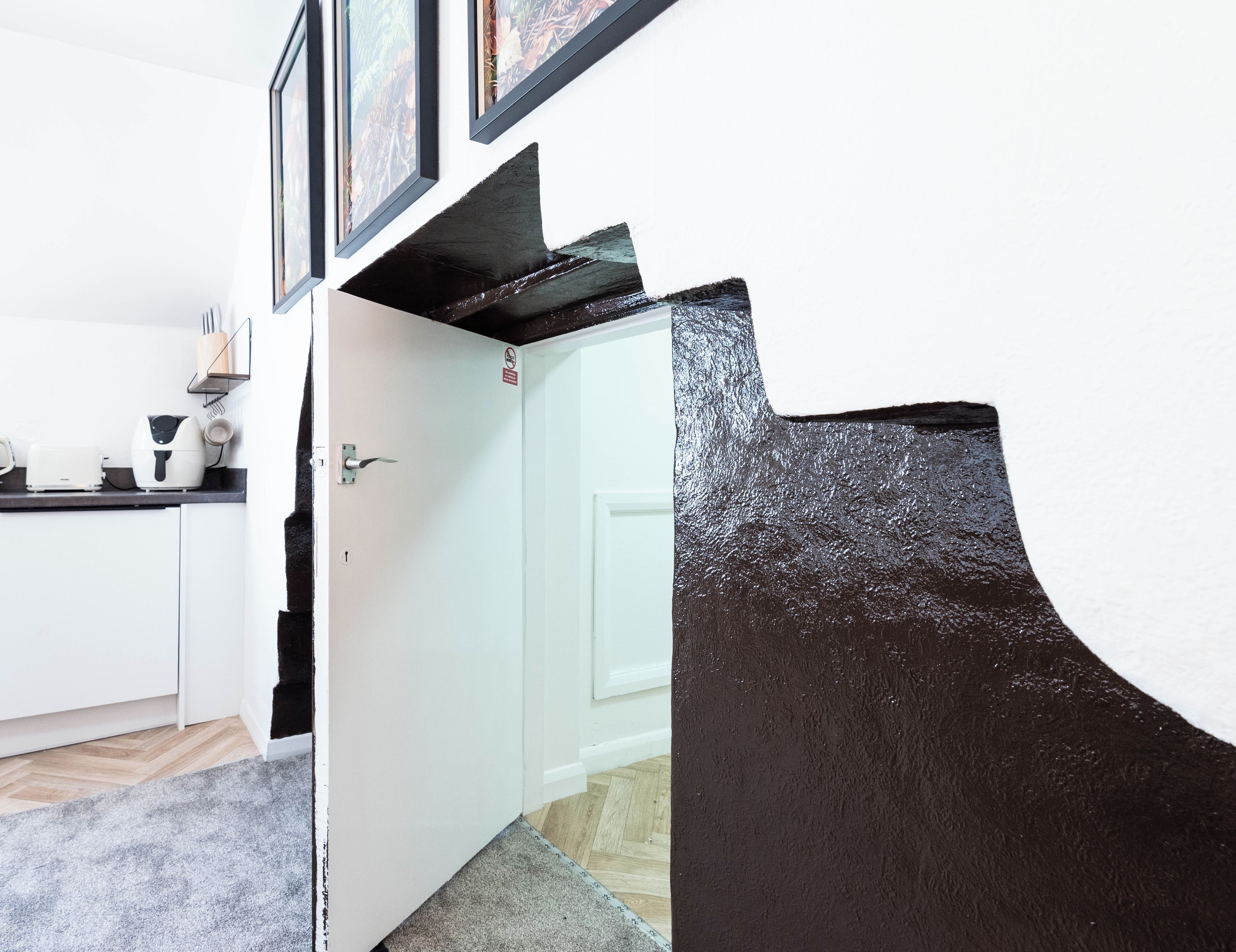 A kitchen with white cabinets, a countertop, and a door with a sign.