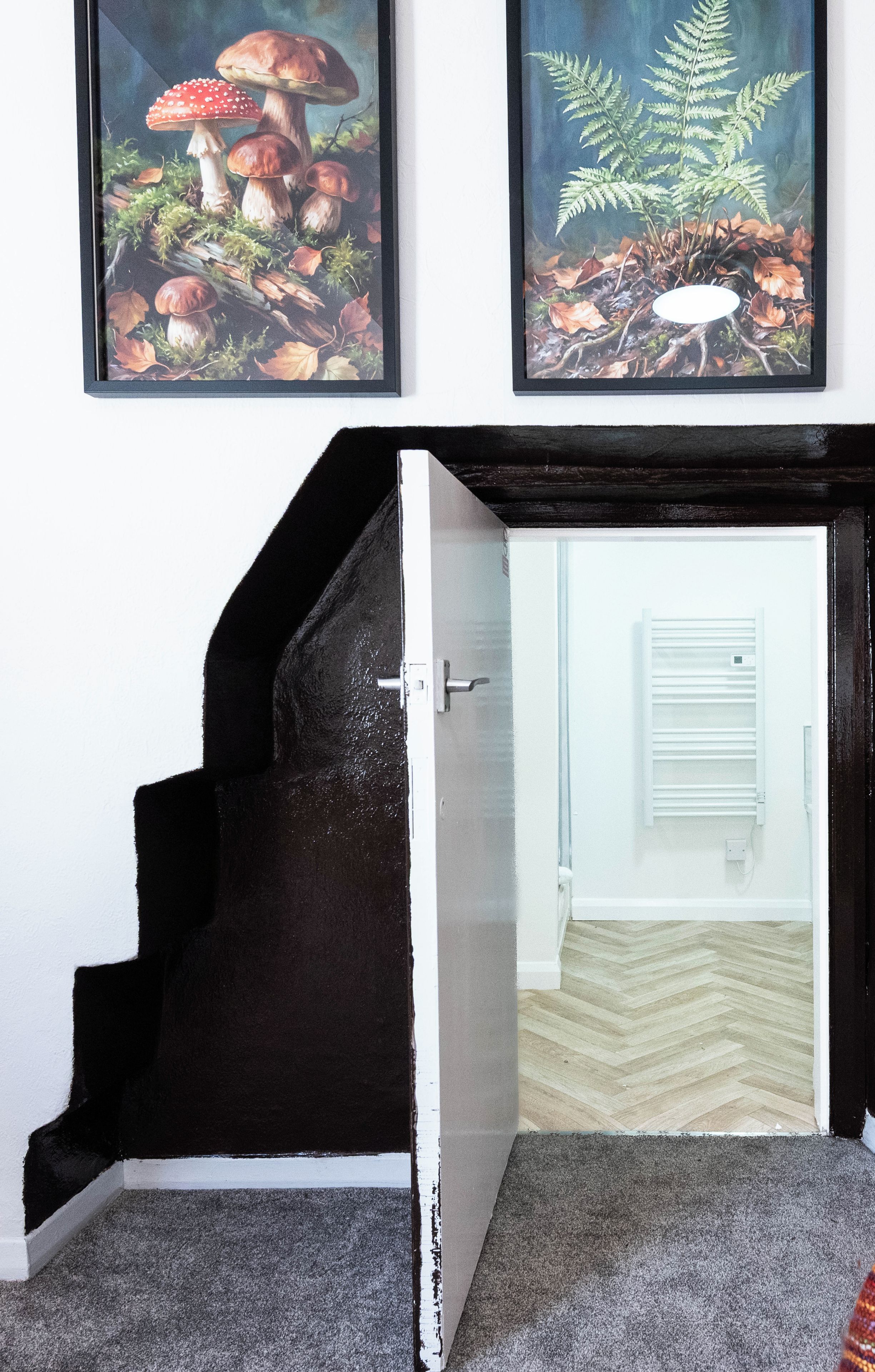 A staircase leading to a room with a white door, a radiator, and a herringbone-patterned floor.