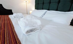 A hotel room with a neatly made bed, a striped area rug, and a green upholstered headboard. - The Stanley Arms Hotel by Guestz (Seascale)