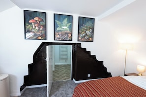A hotel room with a bed, a nightstand, a lamp, and three framed pictures on the wall.