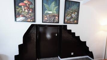 A staircase with a black handrail and a door, leading to a room with a white wall.
