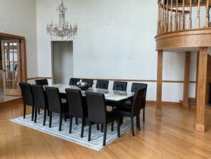 Una sala menjador amb taula de marbre, cadires negres, un penjallum i una escala de fusta.