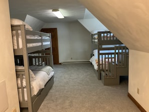 Una habitació amb dos llits superposats, una porta de fusta i una làmpada al sostre.