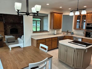 A kitchen with a central island, wooden cabinets, and a stone fireplace.