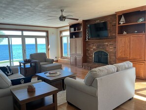 A spacious living room with a fireplace, comfortable seating, and a large TV.