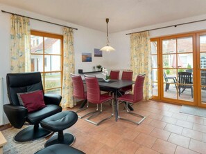 A dining area with a table and chairs, a sofa, and a view through a glass door. - 7/t5 Holiday Home Park \"freesenbruch\" (Zingst)