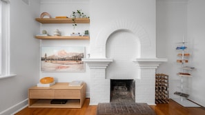 A modern living room with a white brick fireplace, wooden shelves, a painting, and a bookcase. - Brighton Vale, St. Kilda (St Kilda)