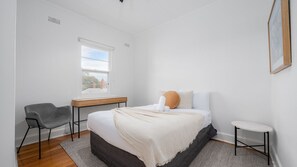 Ein Schlafzimmer mit einem Bett, einem Schreibtisch, einem Stuhl und einem kleinen Tisch.