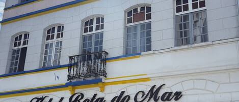 A building with a sign reading 'Hotel Rota de Mar' and a balcony with a statue.